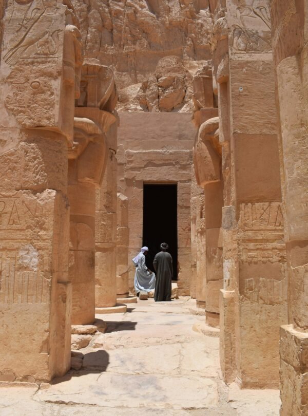 Two individuals exploring an ancient Egyptian temple in Luxor's historic archaeological site.
