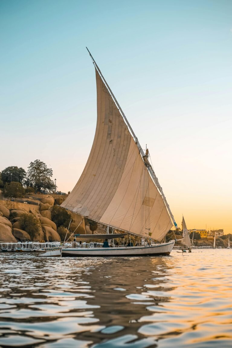 Scenic view of a traditional Egyptian felucca sailing at sunset on the Nile.