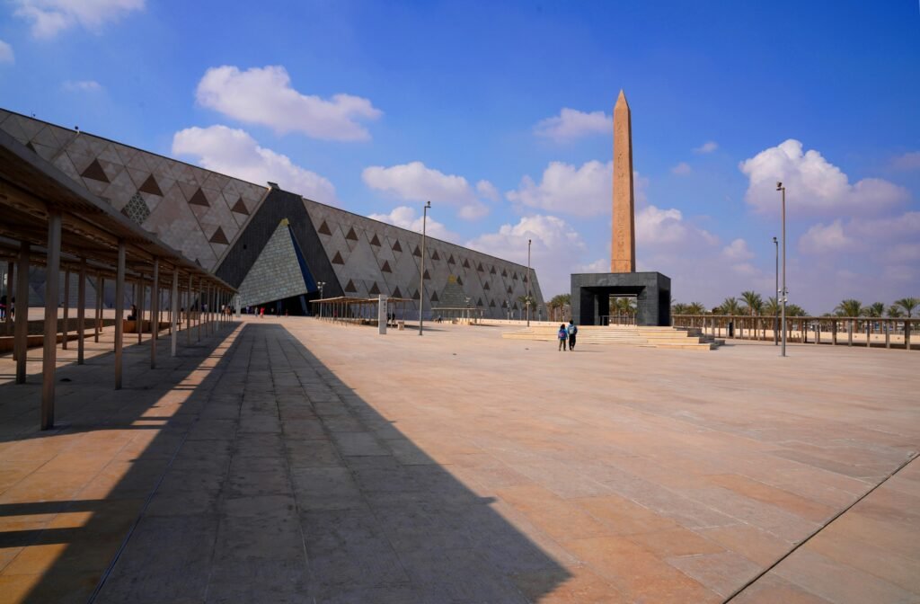 Wide-angle view of the Grand Egyptian Museum with a prominent obelisk and clear skies.