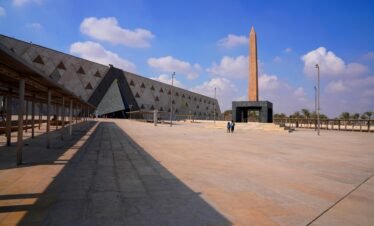 Wide-angle view of the Grand Egyptian Museum with a prominent obelisk and clear skies.